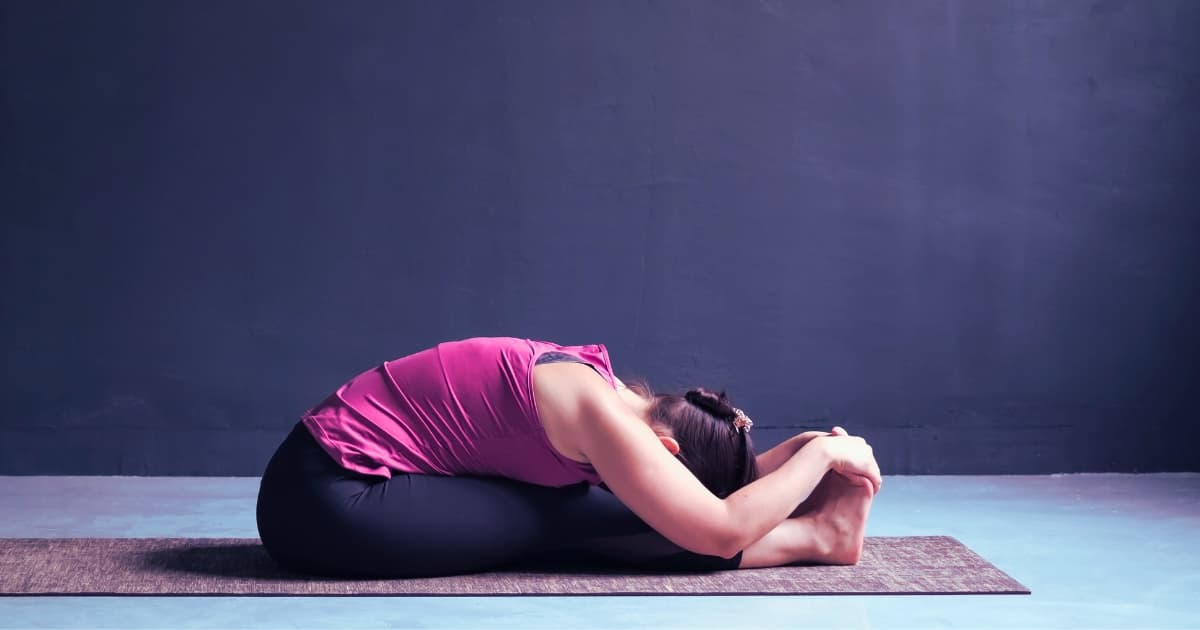 Woman practicing seated forward fold pose as part of gentle morning yoga stretches routine