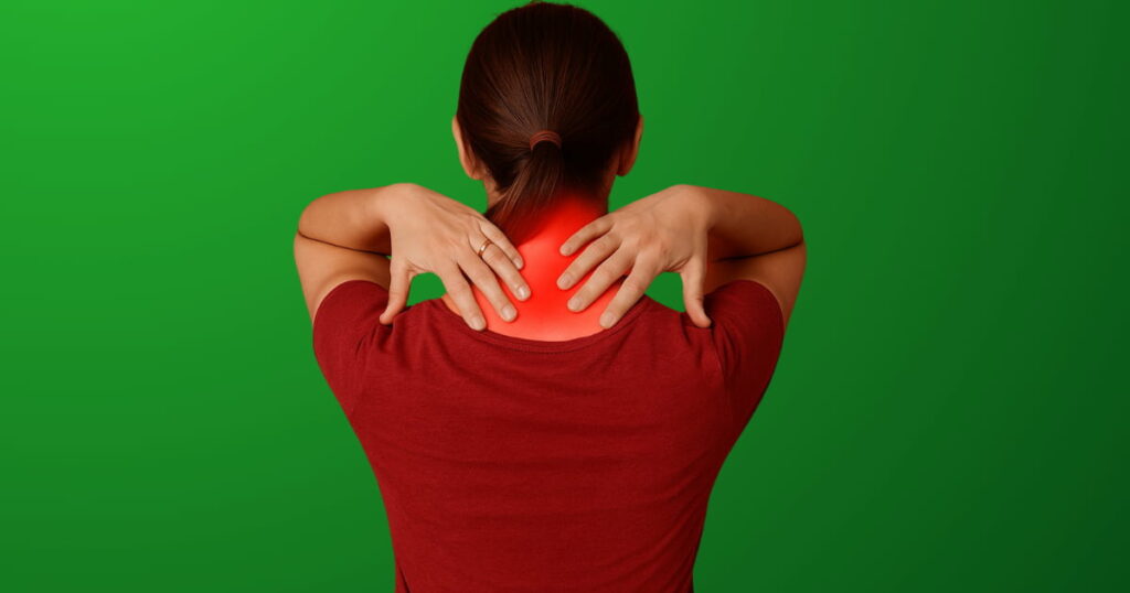 Woman experiencing neck pain relief while holding the back of her neck against a green background