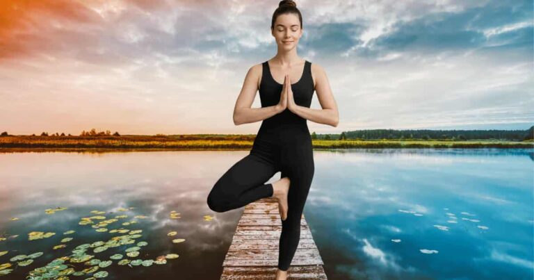 Young woman in a dark dress practicing Hatha Yoga pose peaceful outdoor setting during morning light