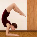 A young woman performing Scorpion Pose in yoga, balancing on her forearms with arched legs, showing strength, flexibility, and control.