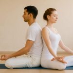 Couple practicing partnered Tantra Yoga in a peaceful studio setting, sharing a meditative breath moment together.