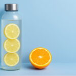 Realistic glass water bottle with lemon slices and measurement markings on a blue background, showing daily hydration goals